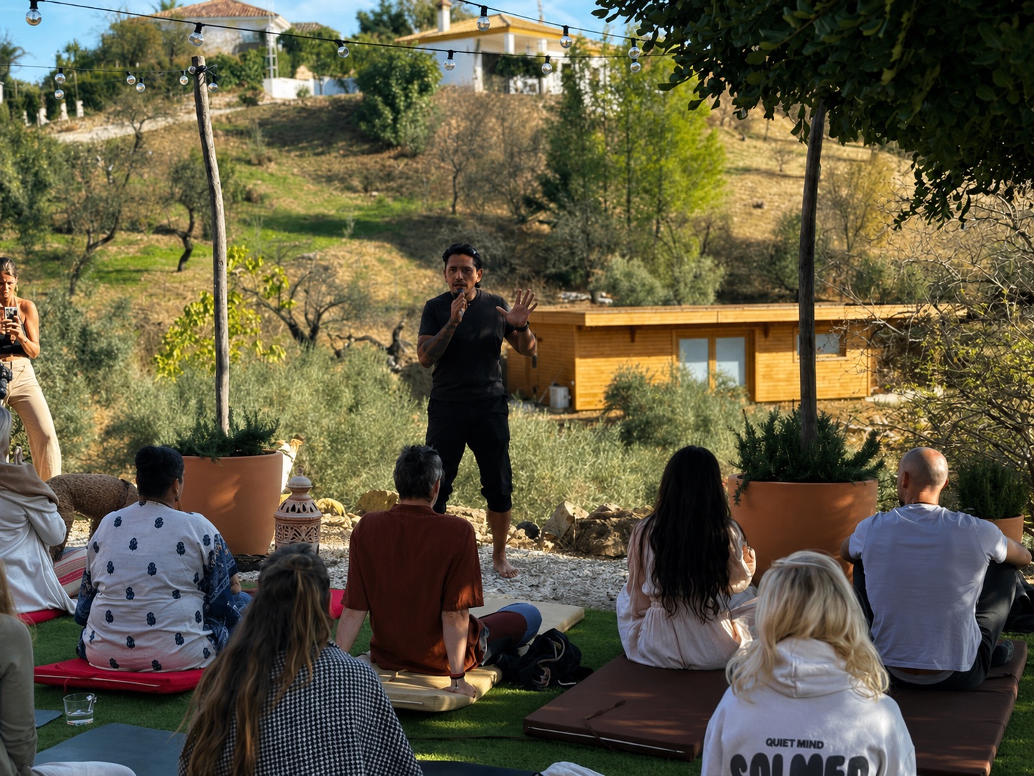 Oscar Trelles speaking to a seated outdoor audience with a microphone